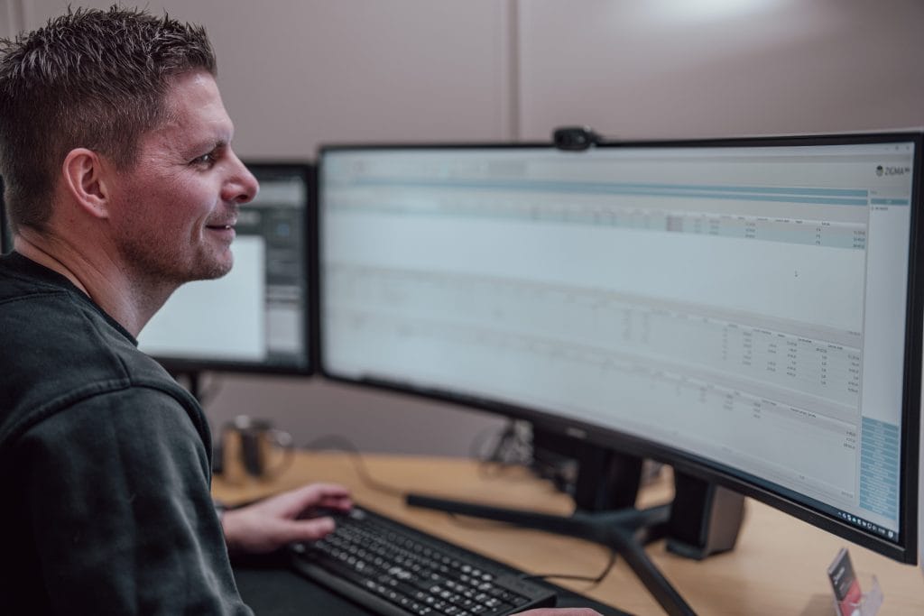 Mann ser på en stor pc-skjerm og smiler.