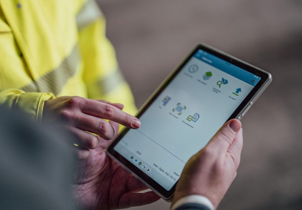 Viser Zigma ERP på et nettbrett, med to mennesker som bruker det. Foto.